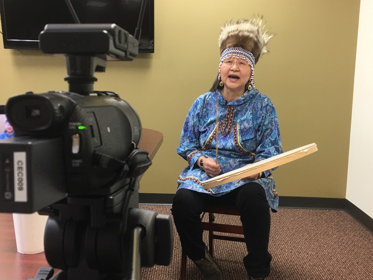 Video production shoot of an Alaska native woman in headdress and drum.