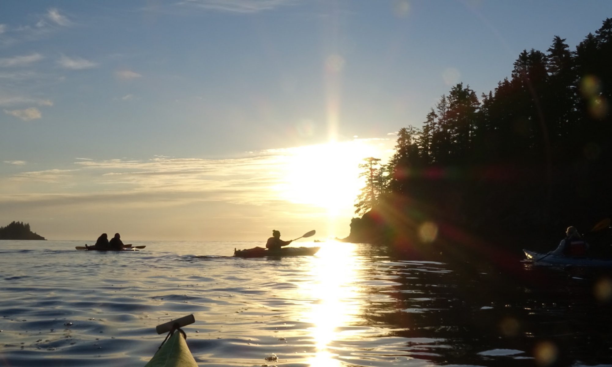 Kayakers paddling in the ocean with a sunset.